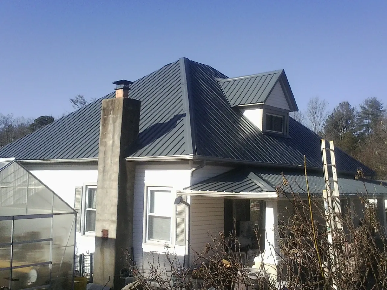 Dark blue standing seam metal roof on a white farmhouse with dormer — Slate & Tile Roof Repair by Roofing Brothers in Rye Beach