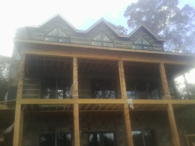 Dormers and porch framing on a large log home under construction — Roof Coating work by our crew in Rye Beach