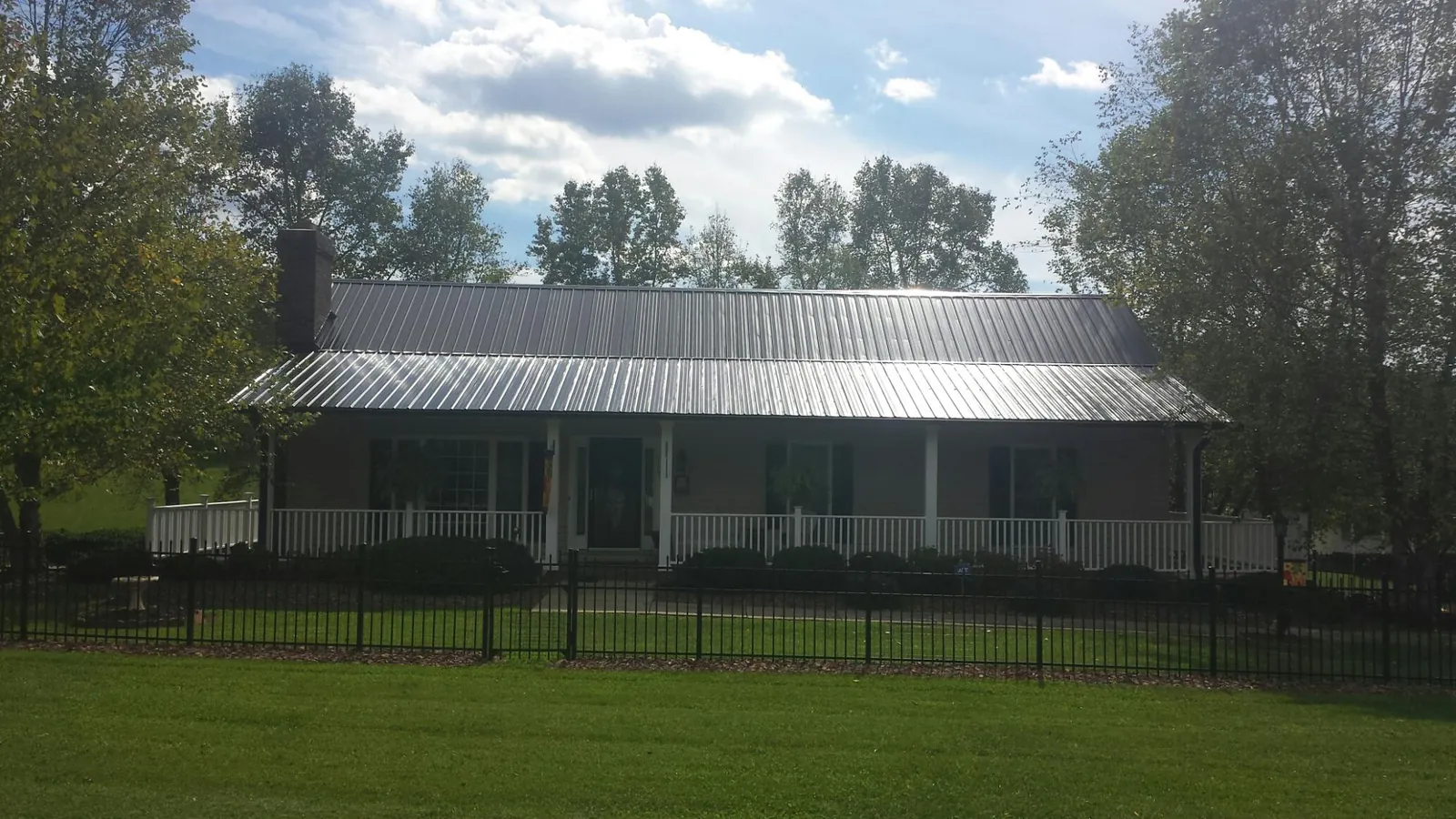 Gray metal roof on a brick ranch with a full width front porch — Gutter Guard Installation work by our crew in Rye Beach