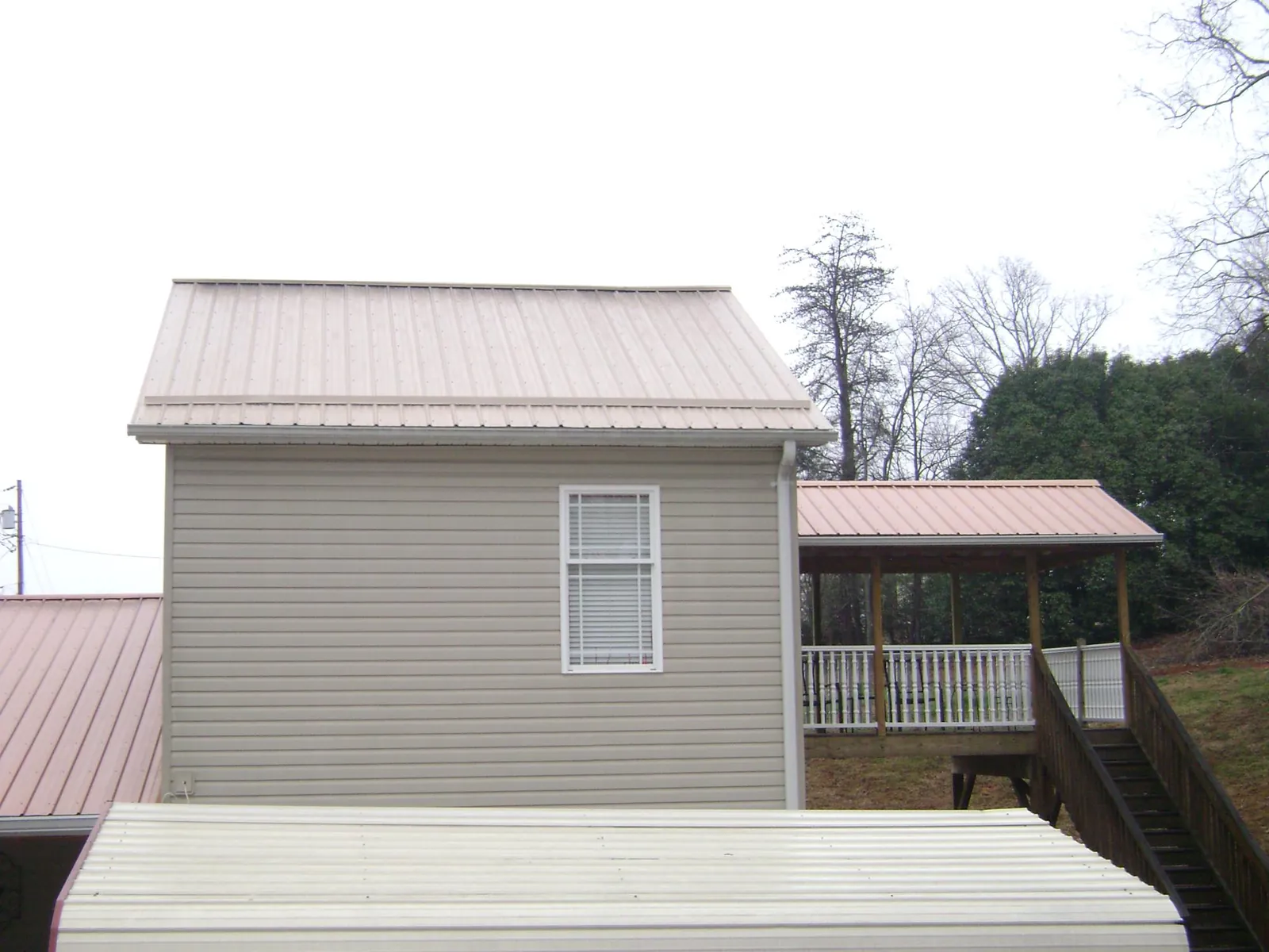 Tan metal roofs on a two story addition and attached porch, from a Roof Replacement job in Rye Beach